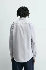 Camisa slim fit blanca de manga larga, cuello italiano y puños con botón. Cierre frontal de botonadura.