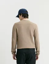 Sweater de punto con textura waffle, color negro, de corte clásico con cuello redondo y mangas largas con puños ajustados.