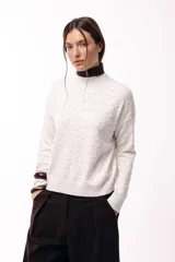 Sweater de tejido de punto con textura en relieve y diseño geométrico sutil. Presenta cuello redondo, mangas largas y terminaciones en tejido acanalado, con un calce relajado.