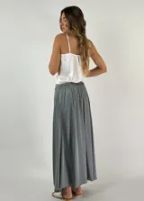Pollera larga de corte evasé, confeccionada en mezcla de viscosa y seda, de tiro alto y caída fluida.