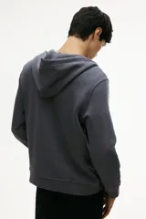 Campera con capucha de felpa color gris oscuro, con cierre frontal, cordón ajustable en la capucha, bolsillos laterales y puños y bajo acanalados. Corte estándar.