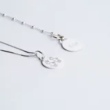 Conjunto de cadena fina y medalla circular de plata 925, con grabado lineal de figuras infantiles en el frente.