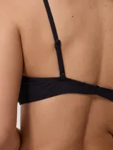 Top de bikini deportivo color negro, con escote redondo y breteles finos ajustables. Presenta el logo de la marca estampado en blanco en la parte inferior izquierda.