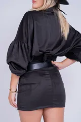 Minifalda negra de gamuza sintética con tajo lateral y cinturón con tachas plateadas.