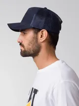 Gorra tipo trucker color azul marino con diseño de 5 paneles, visera curva y parte trasera de malla. Cuenta con un parche frontal con el logo de Caterpillar.