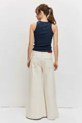 Pantalón denim de corte wide leg, tiro alto y color crudo con costuras en contraste.