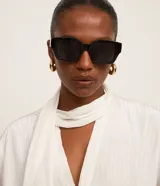 Blusa blanca de manga larga con textura satinada, escote en V y cuello con lazo.