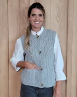 Chaleco tejido de punto con diseño de ochos, color gris, con cierre frontal de botones y bolsillos delanteros aplicados.