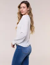 Blusa negra de silueta semi entallada confeccionada en rayón. Presenta un escote en V pronunciado con cuello mao fruncido, pechera con textura elástica en punto smock, mangas largas fluidas con frunces en los hombros y puños anchos.