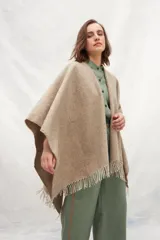 Ruana de lana 100% sin teñir en color tostado, con diseño de punto acanalado y terminación de flecos en el ruedo.
