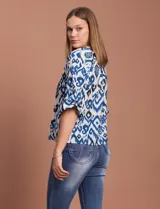 Blusa de gasa estampada en tonos azules y negros, marca Sioni. Tiene cuello a la base con escote en V, abertura central con botones y mangas tres cuartos fruncidas.