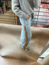 Pantalón de jean de corte recto y tiro medio, con detalle de flecos laterales largos en cuero genuino.