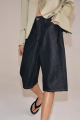 Bermuda de denim en color azul oscuro, de tiro medio con cintura con trabillas. Presenta costuras con pespuntes en color contraste, bolsillos laterales y cierre frontal con cremallera y botón metálico.