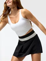 Top deportivo blanco con costuras visibles tipo corseteras en el pecho, tirantes delgados y espalda rebajada.