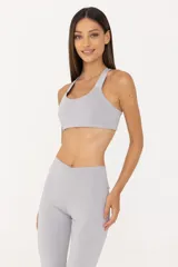 Top deportivo gris claro de poliéster y elastano, con espalda descubierta, breteles finos y banda elástica inferior.