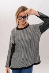 Sweater de punto con cuello redondo y mangas largas. Diseño a rayas verticales en tonos gris y negro.