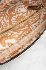 Bandolera con estampado animal print, correa ancha negra regulable y bolsillo frontal con cierre a presión.