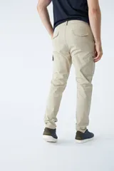 Pantalón cargo de corte slim, color negro, con bolsillos laterales con solapa y botones metálicos. Cuenta con cierre frontal, botón en la cintura y pasacintos.