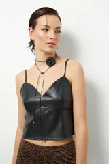 Top negro de símil cuero con escote en V, sin mangas, pinzas y corte en la cintura. Cierre metálico en la espalda.