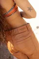 Bermuda de cuero color marrón oscuro con efecto desgastado, tiro medio, cierre frontal con botón y bolsillos.