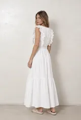 Vestido largo beige con escote en V cruzado, mangas con volados de broderie y cintura elastizada fruncida. La falda larga cuenta con un volado fruncido en el ruedo.