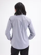 Camisa de corte clásico con estampado de rayas verticales finas en color azul y blanco, cuello camisero y cierre frontal con botones.