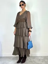 Vestido largo de seda italiana color chocolate, con escote en V, mangas largas abullonadas y diseño de falda con volados escalonados.