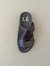 Sandalias de cuero color marrón con diseño asimétrico de tiras y plantilla anatómica. Tienen ajuste lateral con velcro y suela plana.