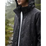 Campera cortaviento impermeable de la marca Uniteduy, color negro con estampado sutil de hojas. Cuenta con capucha, cierre frontal, tres bolsillos externos y uno interno. Es una prenda ultra liviana y transpirable, ideal para actividades al aire libre.