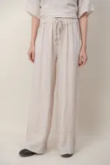 Pantalon de lino color azul, de corte ancho y relajado, con cintura elastizada ajustable mediante cordón y bolsillos laterales. Presenta detalles de alforzas en los bajos.