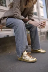 Championes de cuero negro con suela de caucho y cordones negros, con detalles de tachas metálicas en los laterales.
