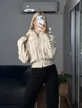 Saco tejido de punto con diseño de ochos, cuello con detalle de piel sintética, cierre frontal con botones al tono y mangas largas.