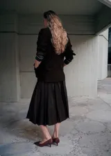Falda midi plisada de cuero sintético en color marrón oscuro, con diseño acampanado y talle alto.