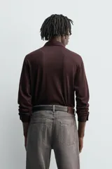 Camisa de manga larga color marrón oscuro, con cuello solapa y cierre frontal de botonadura. El tejido es semitransparente y presenta una textura jacquard.