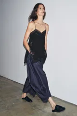 Top lencero de escote en pico con tirantes finos, confeccionado en tejido fluido con aplicaciones de encaje a tono en el escote, laterales y bajo. Presenta aberturas laterales en el ruedo.