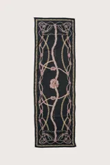 Pareo rectangular de tela ligera con estampado de cadenas y nudos náuticos en tonos dorados y beige sobre un fondo negro.