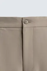 Pantalón de corte relajado en color verde militar, con diseño de pliegues frontales, bolsillos laterales y cierre de cremallera con botón.