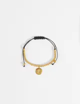 Pulsera ajustable de cordón negro con cuentas doradas y un dije central circular con diseño de estrella grabada.