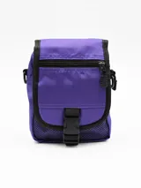 Bolsito tipo morral color violeta con detalles en negro. Cuenta con un compartimento principal con solapa y cierre de hebilla, un bolsillo frontal con cierre y bolsillos laterales de red.