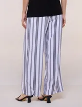 Enterito de efecto dos piezas con parte superior negra lisa, escote en V y sin mangas, y parte inferior de pantalón palazzo de corte amplio con diseño a rayas en blanco y negro. Cuenta con cintura entallada con lazo ajustable.