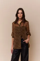 Camisa marrón de gasa con estampado animal print, corte clásico, mangas 3/4 con puños elásticos, cartera de botones negros y logo bordado en rojo.
