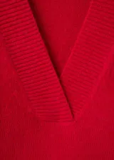 Jersey de punto grueso color rojo, con cuello en V profundo y mangas largas de corte recto.