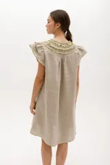 Vestido negro de lino, corte suelto, con cuello redondo con volados y mangas cortas con volados.