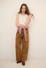 Jean tostado de corte wide leg, tiro medio con presillas y lazo ajustable en la cintura. Presenta bolsillos delanteros y traseros, costuras decorativas verticales y terminación desmechada en el ruedo.