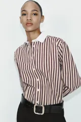 Camisa de manga larga con estampado de rayas verticales en tonos marrón y beige. Presenta cuello solapa y puños anchos en color blanco a contraste, con cierre frontal de botones.