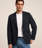 Blazer azul marino de tejido texturizado, con cuello solapa, abotonado delantero, mangas largas y bolsillos. Corte clásico.