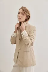 Blazer sastrero de lino color beige, de silueta relajada y líneas clásicas. Incorpora solapas tradicionales, cierre frontal de un botón y bolsillos de vivo.