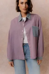 Camisa lila de calce relajado y manga larga, con cuello clásico, puños y bolsillo delantero en denim contrastante. Cierre frontal con broches metálicos.