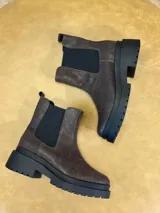 Bota estilo Chelsea de cuero con textura, color marrón oscuro, con paneles elásticos laterales negros y suela de plataforma dentada de goma negra.