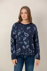 Sweater de punto con textura suave, color azul marino con estampado de formas abstractas y rombos en tonos celestes y grises. Presenta cuello redondo y mangas largas con diseño holgado.